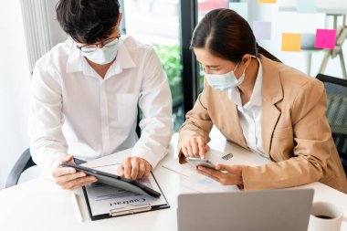 İki iş arkadaşı, hijyenik koruma altında imzayı atmadan önce sözleşmeyi gözden geçirmek için birbirlerine yardım ediyorlar..