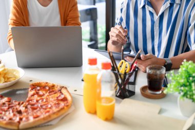 İş dünyası çalışanları iş hakkında tartışıyor ve öğle yemeği arasında yemek için pizza ve patates cipsi hazırlıyorlar.