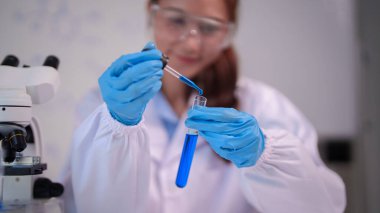 Yetişkin Asyalı kadın araştırmacı laboratuarda kimya deneyi yapıyor. Bilimsel analiz ve keşif için sıvı transferi.