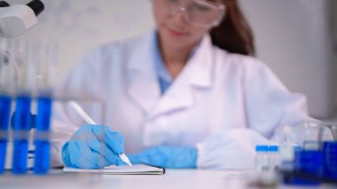 Kendini adamış kadın araştırmacı tıbbi keşif için kritik deney analizleri sırasında bilimsel gözlemleri laboratuvar ortamında özenle kaydediyor.