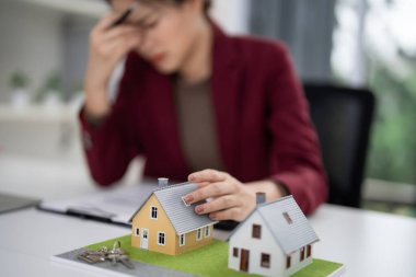 Profesyonel emlakçı önemli konut piyasası seçeneklerini göz önünde bulundurarak baskı hissediyor. Masada konut modelleri ve emlak planlaması için anahtarlar gösteriliyor.