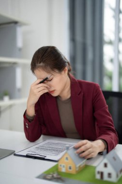 Asyalı kadın simsar, emlak sözleşmelerini incelemek ve konut piyasası ile ilgili zor kararlarla boğuşmak gibi önemli bir iş stresi yaşıyor