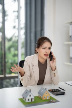 Adanmış emlakçı müşteriyle telefon görüşmesi yapar. Mesleki çalışma alanından satış ve emlak işlemlerini yönetiyor..