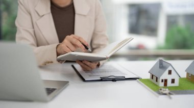 Profesyonel emlakçı, emlak belgelerini ve ev modellerini dikkatle inceler. Satışa hazırlık ve müşteri danışmanlığına odaklan.