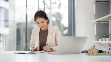 Profesyonel Asyalı kadın gayrimenkul anlaşmalarını titizlikle analiz ediyor başarılı emlak yatırımları ve müşteri işlemlerini planlıyor