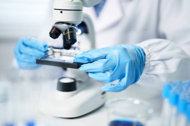 Laboratuar uzmanı detaylı analiz için mikroskobu dikkatlice ayarlar. Modern laboratuarda tıbbi araştırma ve geliştirme ilerlemekte olan sağlık hizmetleri.