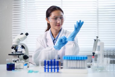 Gelişmiş laboratuvar deneyleri için kendini adamış Asyalı bilim adamı. Tıbbi araştırma ekipmanlarını odaklama ve hassasiyetle kullanan profesyonel yetişkin bir kadın..