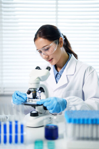 Diligent female researcher in protective gear performing medical analysis at a modern laboratory setting ensuring accurate discovery