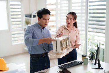 Asyalı mimarlar mimari yapı modelini gözden geçiriyorlar. Profesyonel yetişkinler yenilikçi tasarım çözümlerini tartışırlar. Takım çalışması proje planlaması.