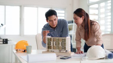 Profesyoneller modern bir ofisin mimari model yapı planlarını analiz ederek işbirliği yaparlar. Kentsel kalkınma ve emlak yatırımları için stratejik planlama.