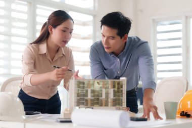 İki odaklı Asyalı yetişkin mimari bir model üzerinde işbirliği yapar. Modern ofis ortamlarında titizlikle bir inşaat projesi planlıyorlar..