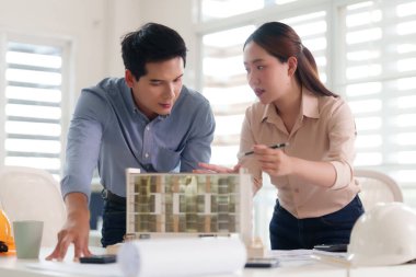 Asyalı yetişkin mimarlar modern ofis ortamını tartışan bina modelleri tasarlıyorlar. Takım çalışması profesyonel mühendislik planlaması.