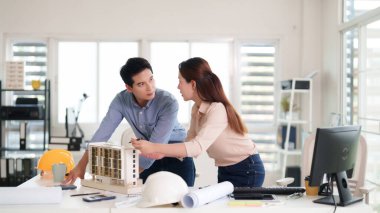 Asyalı profesyonel mimarlar model tasarım planlarını tartışıyor. Takım çalışması şehir inşaat konseptini geliştirme projesi. Odaklanmış yaratıcı çalışma alanı.