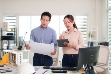 Asyalı profesyoneller inşaat planlarını, modern ofis modelini, takım çalışmasını, başarılı mimari mühendislik projesi geliştirme işbirliğini analiz ediyorlar.