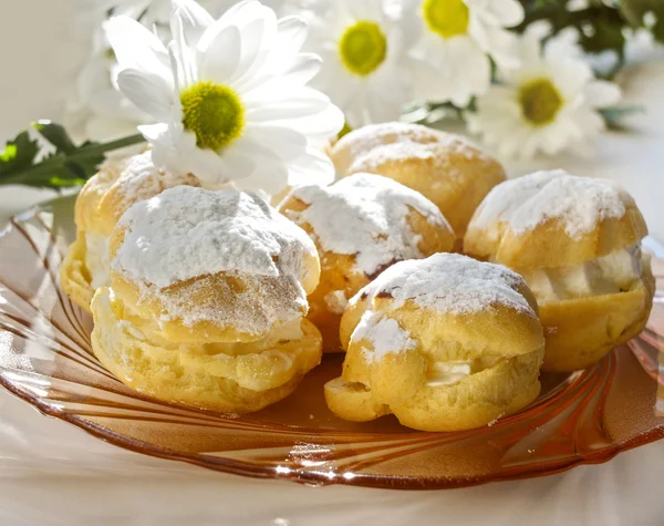 Cream puff or profiterole with filling and powdered sugar topping, isolated, against white background — Stock Photo, Image