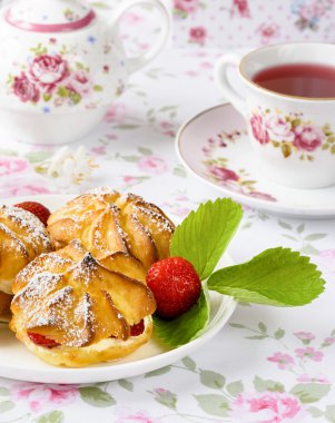 Krem puffs veya profiterol krema ile doldurulmuş, pudra şeker tepesi ile çilek masaya servis