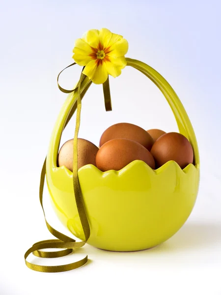 Basket of Easter eggs with flower and ribbon — Stock Photo, Image