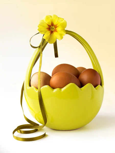 Basket of Easter eggs with flower and ribbon — Stock Photo, Image