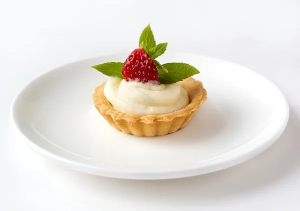 Liten cupcake med jordgubb, vispad grädde och mynta på en vit platta — Stockfoto