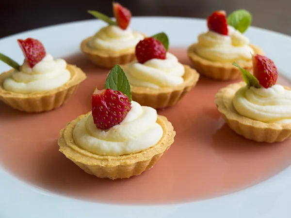 Små muffins med jordgubbar, vispad grädde, gelé och mynta — Stockfoto