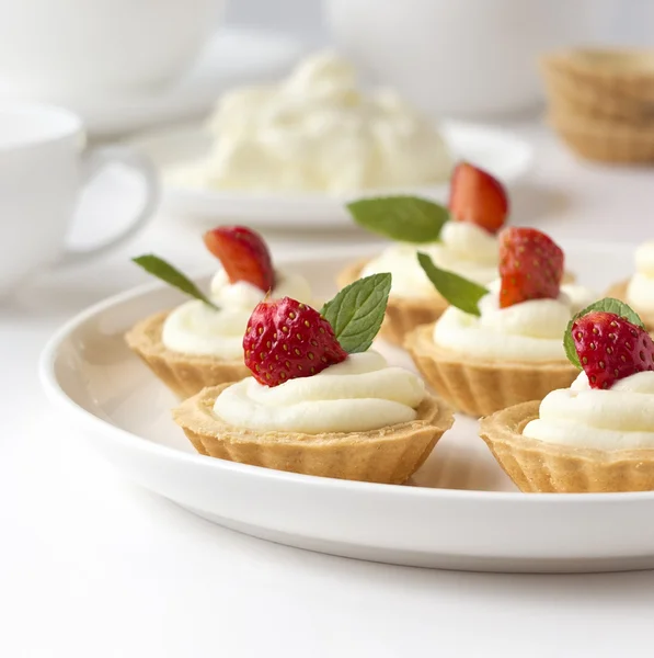 Veel cakes, cupcakes met vers fruit (aardbeien), opgeklopte room, gelei en pepermuntjes — Stockfoto