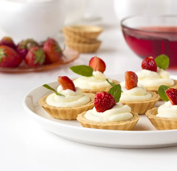 Viele Kuchen, Cupcakes mit frischen Früchten (Erdbeeren), Schlagsahne, Gelee und Minzen — Stockfoto