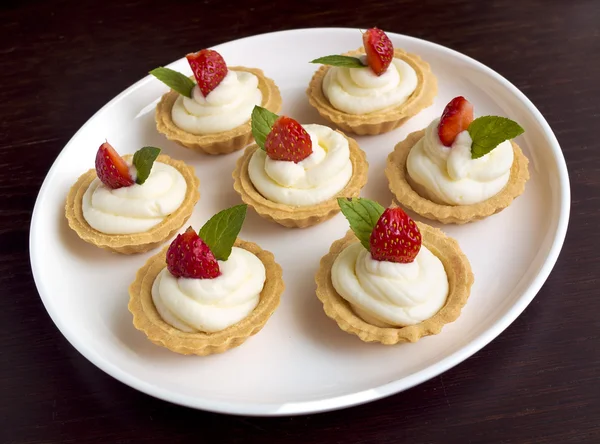 Viele Kuchen, Cupcakes mit frischen Früchten (Erdbeeren), Schlagsahne und Minzen — Stockfoto