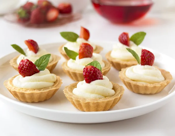 Viele Kuchen, Cupcakes mit frischen Früchten (Erdbeeren), Schlagsahne, Gelee und Minzen — Stockfoto