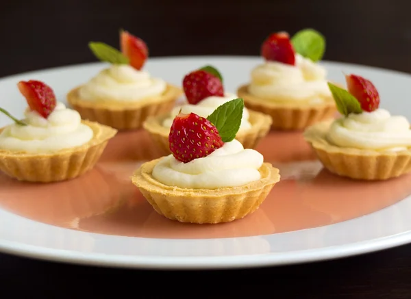 Små muffins med jordgubbar, vispad grädde, gelé och mynta — Stockfoto