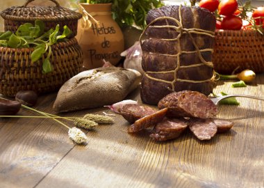 Kurutulmuş tavla salam ve sosis ekmek, domates, otlar, sarımsak ve basketson ahşap tahta ile dilim füme