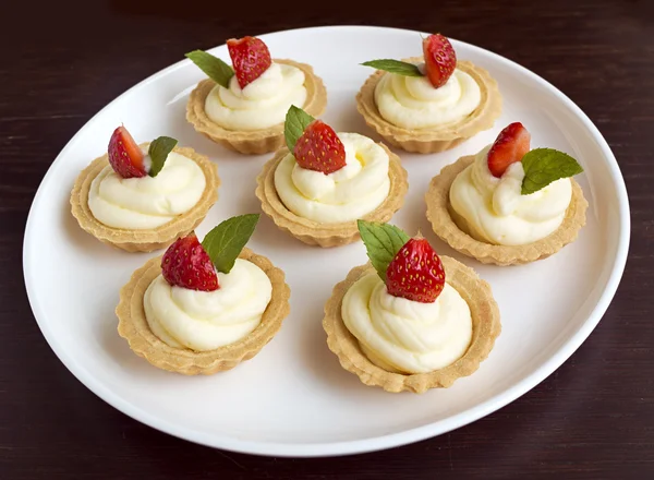 Small biscuits with whipped cream, strawberry, mint on white plate on table — Stock Photo, Image