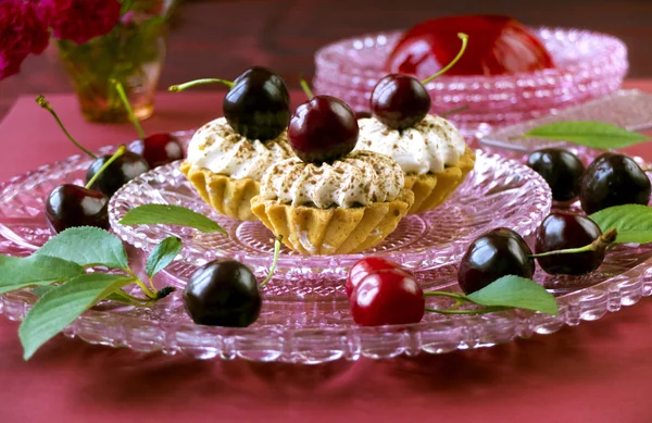 Торты (кексы) с темными вишнями на стеклянной тарелке — стоковое фото