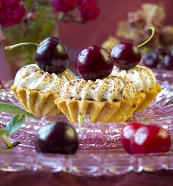 Cakes (cupcakes) with dark cherries on glass plate — Stok fotoğraf