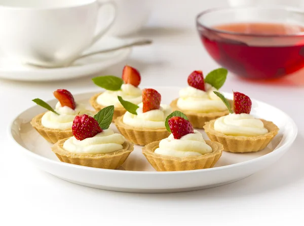 Muchos pasteles, cupcakes con frutas frescas (fresas), crema batida, jalea y menta —  Fotos de Stock