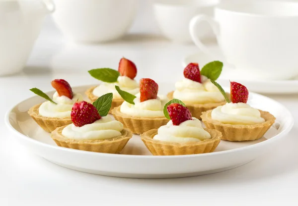 De nombreux gâteaux ou mini tartes aux fruits frais, crème fouettée et menthe — Photo