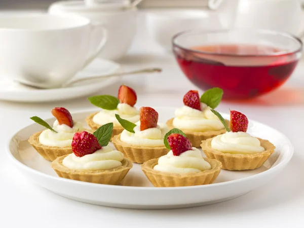 De nombreux gâteaux ou mini tartes aux fruits frais, crème fouettée et menthe — Photo