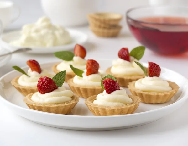 Muchos pasteles o mini tarta con frutas frescas, crema batida y mentas — Foto de Stock