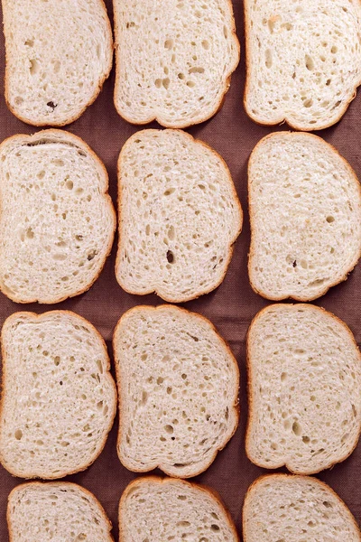 Doze pedaços de pão branco deitado sobre uma toalha de cozinha — Fotografia de Stock