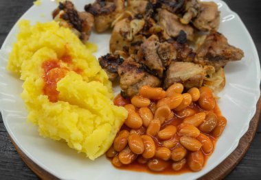 Beyaz fasulyeli patates püresi, et ve soğan yakın plan beyaz tabakta.