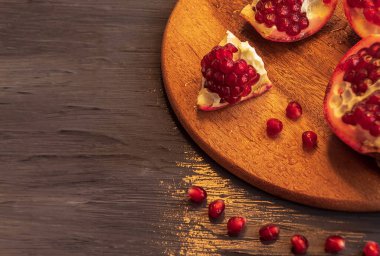 Düz olmayan parçalara ayrılmış sulu nar yuvarlak bir tahtanın üzerinde yatıyor.