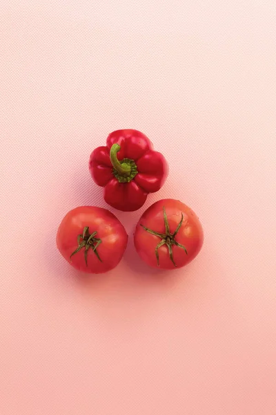 縦の写真はジューシーで健康的な野菜です これらは赤いトマトとピーマンです ピンクの背景に野菜が中心にあります ロイヤリティフリーのストック写真