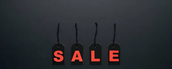 Word sale written on black cardboard paper labels or price tags with cord isolated on dark background. Black Friday, Shopping, sale and marketing concept. Top view, flat lay, copy space.