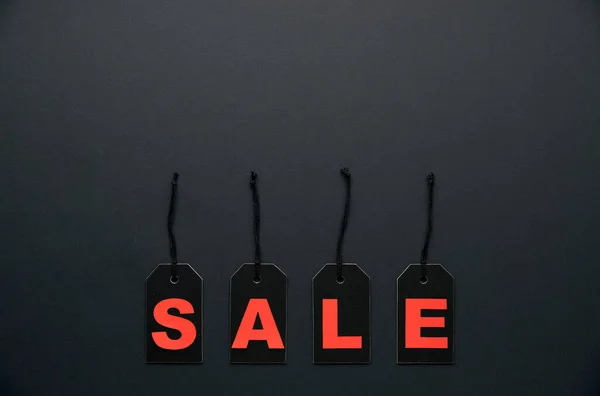 Word sale written on black cardboard paper labels or price tags with cord isolated on dark background. Black Friday, Shopping, sale and marketing concept. Top view, flat lay, copy space.