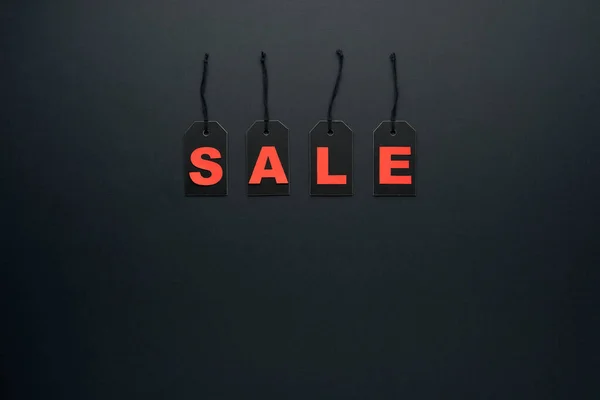 Word sale written on black cardboard paper labels or price tags with cord isolated on dark background. Black Friday, Shopping, sale and marketing concept. Top view, flat lay, copy space.
