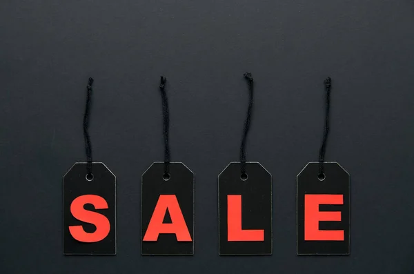 Word sale written on black cardboard paper labels or price tags with cord isolated on dark background. Black Friday, Shopping, sale and marketing concept. Top view, flat lay, copy space.