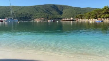 4K Güzel panoramik cennet manzaralı otel kumsalı Lujo beyaz kumlu, yatlı, göl kıyısında Ege Denizi 'nin zümrüt suyuyla kaplı evler, lüks turizm kavramı.