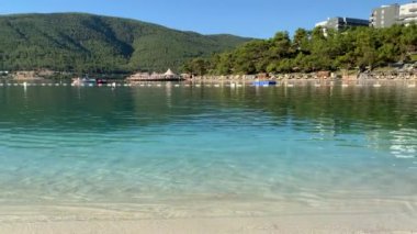 4K Güzel panoramik cennet manzaralı otel kumsalı Lujo beyaz kumlu, yatlı, göl kıyısında Ege Denizi 'nin zümrüt suyuyla kaplı evler, lüks turizm kavramı.