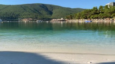 4K Güzel panoramik cennet manzaralı otel kumsalı Lujo beyaz kumlu, yatlı, göl kıyısında Ege Denizi 'nin zümrüt suyuyla kaplı evler, lüks turizm kavramı.