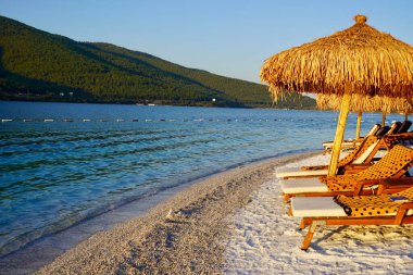 Bodrum, Türkiye - Beyaz kum ve kakao palmiyeleriyle Hotel Lujo 'nun tropikal cennet plajı, 2020 Ağustos' ta güneş şemsiyeli geniş panzeli turizm arka planı kavramı ile seyahat eder. Lüks turizm konsepti