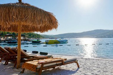 Bodrum, Türkiye - Ağustos 2020 Lux Hotel 'in kar beyazı plajı Ege Denizi' nin zümrüt suyuyla. Yatlar. İnsanlar kumsalda güneşleniyor. Kumsalda güneşli yataklar. Lüks Gebelik Rahatlatıcı. Cennet